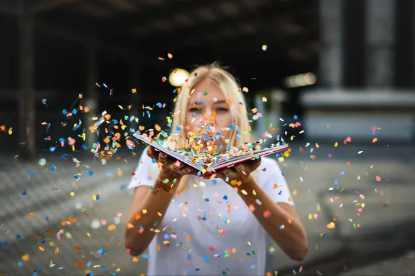 Frau hält Buch mit fliegendem Konfetti