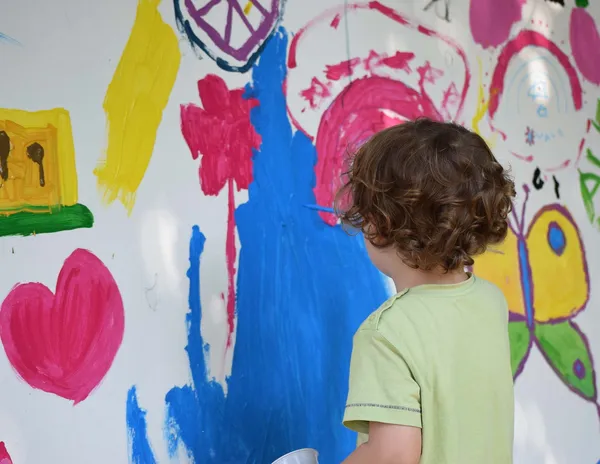 Junge malt mit Farben an die Wand