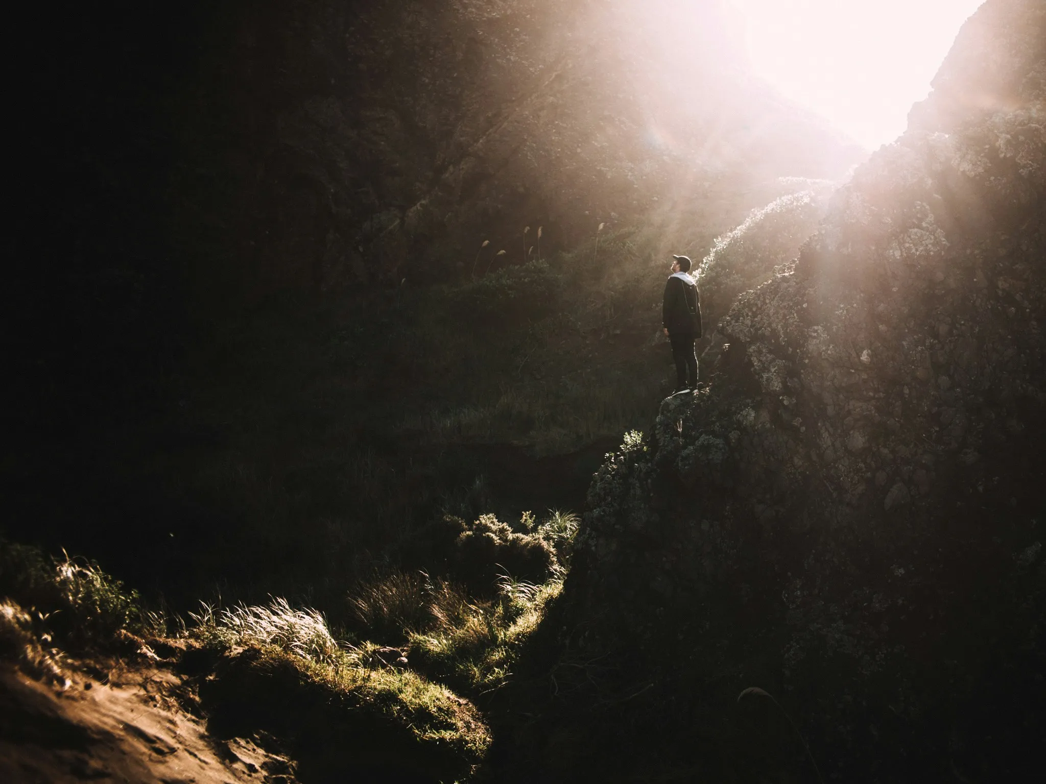 Quelle: unsplash.com /@hillie-chan Mann auf Felsen im Wald, Lichtstrahl von oben