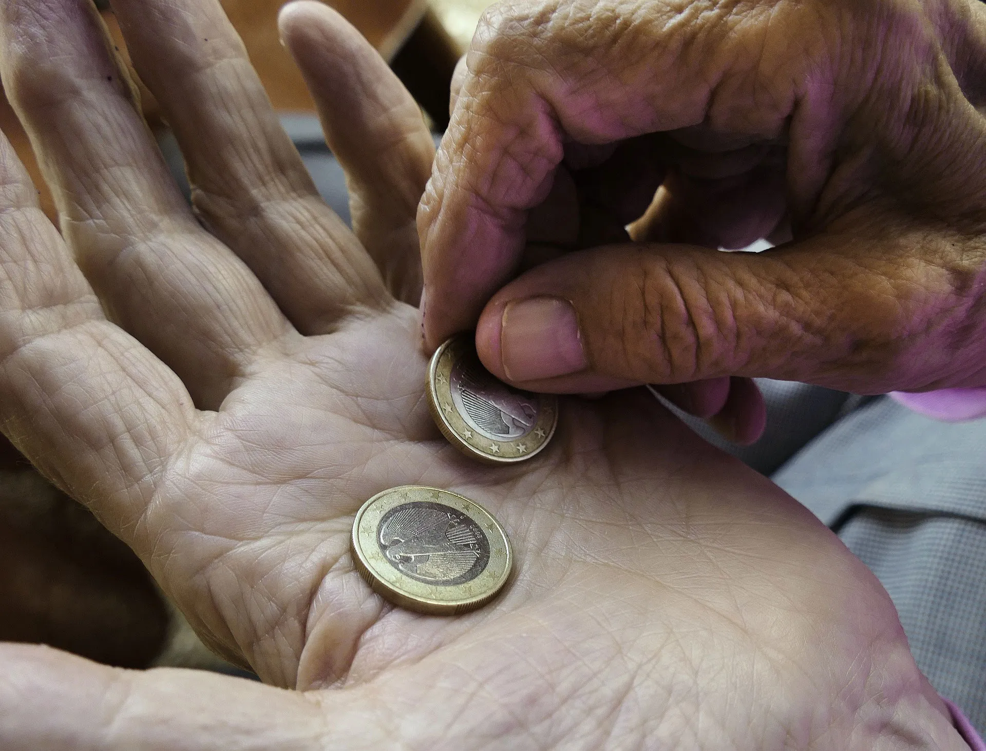 Quelle: pixabay.com / anaterate Hand einer älterern Person mit zwei 2-Euro-Münzen