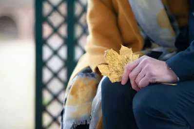 Zwei Menschen sitzen auf einer, eine hält ein verwelktes Blatt in der Hand