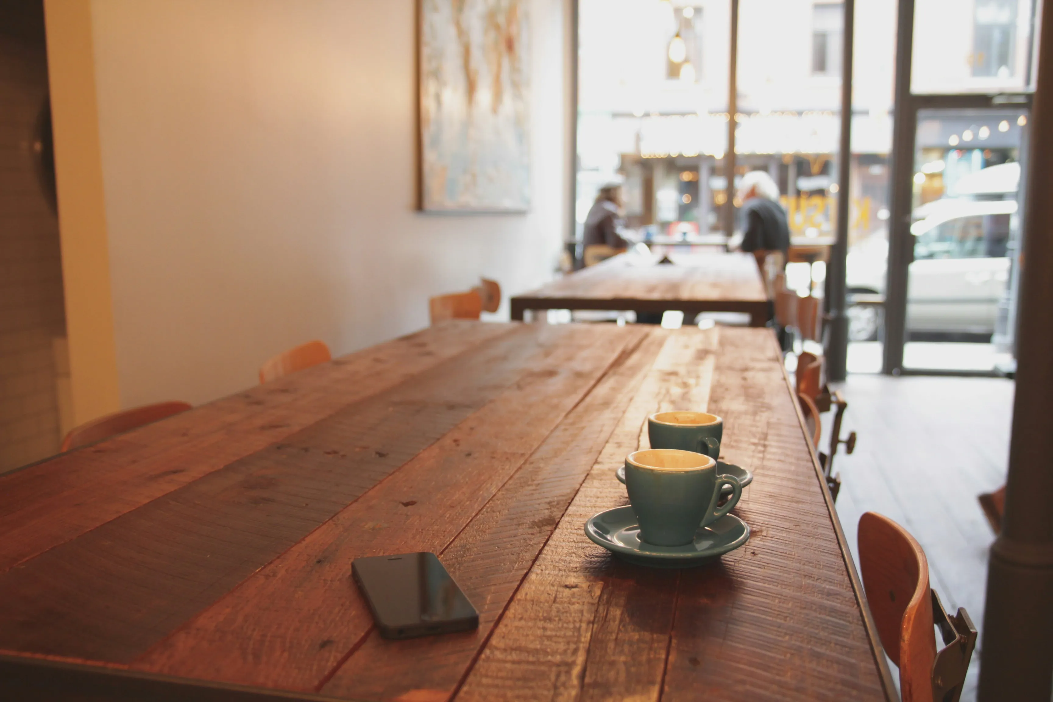 Zwei graue Keramiktassen auf braunem Esstisch aus Holz in Café