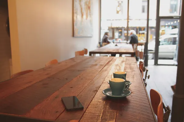 Quelle: Luke Chesser/Unsplash Zwei graue Keramiktassen auf braunem Esstisch aus Holz in Café