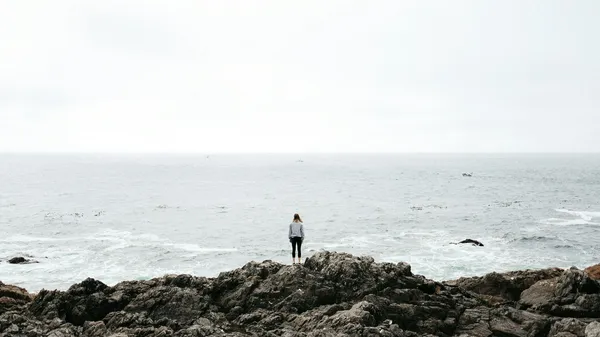Quelle: Sofia Neumann/Unsplash Frau steht auf Felsen vor dem Meer