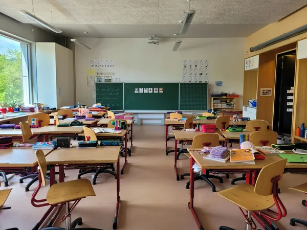 Quelle: Nathan Cima/Unsplash Klassenzimmer mit Tischen und Stühlen, Blick auf die Tafel