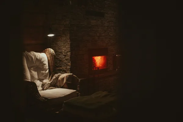 Quelle: Bjarne Postma/Unsplash Gemütlicher Sessel mit Decke neben brennendem Kamin