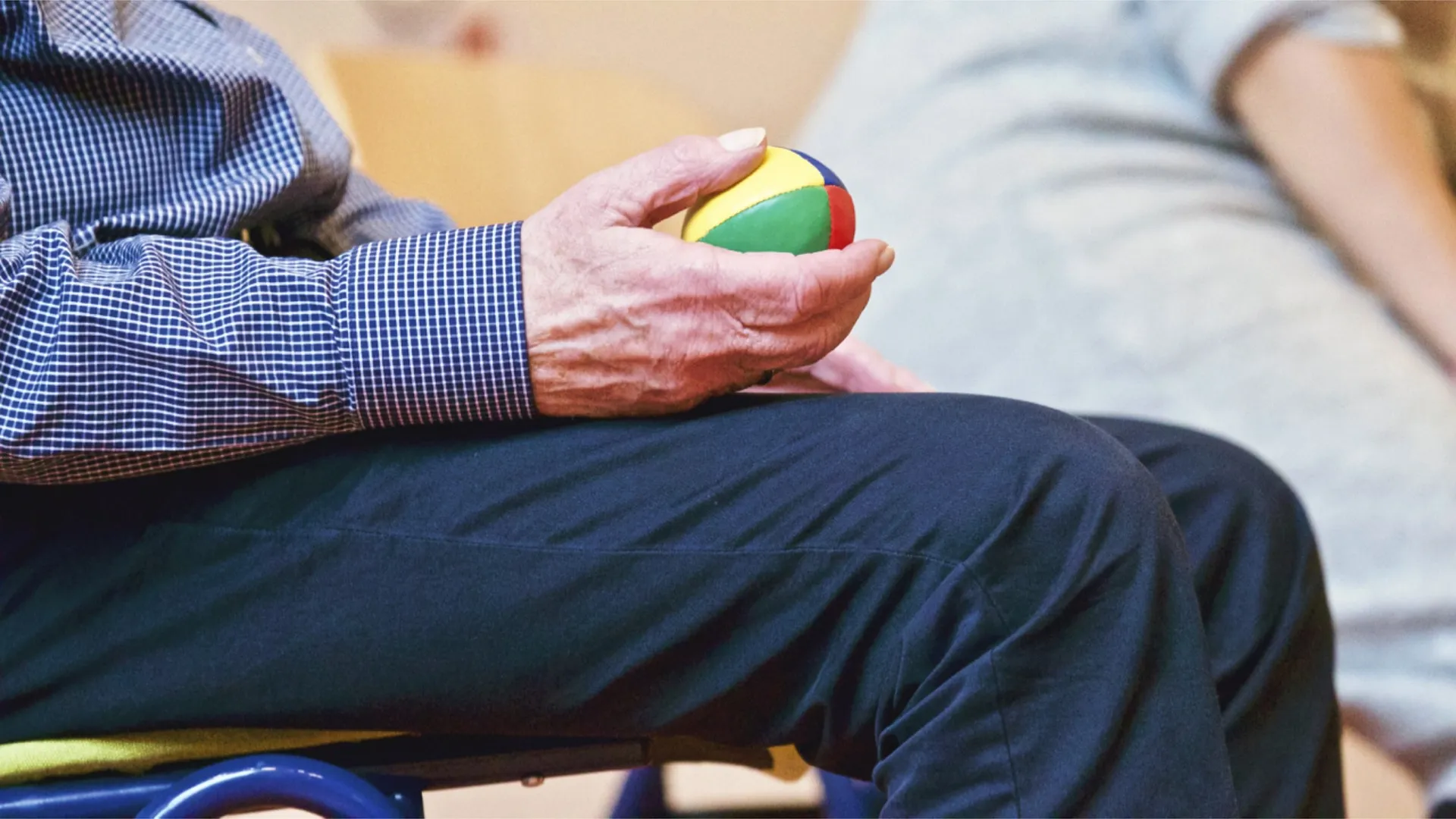 Alter Mann auf einem Stuhl mit Ball in der Hand