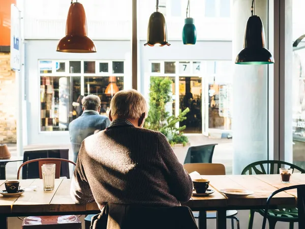 Quelle: Jeff Sheldon/Unsplash Mann sitzt im Café und schaut nach draußen