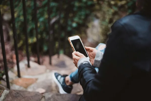 Quelle: Chad Madden/Unsplash Person mit weißem Smartphone sitzt auf einer Treppe im Freien
