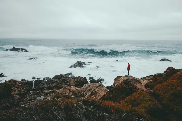 Quelle: Kyle Loftus/Unsplash Mann auf Felsformation vor Küste