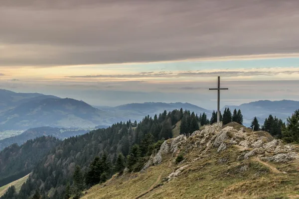 Quelle: Thanti Riess/Unsplash Blick von einer Anhöhe über Berge, mit großem Kreuz
