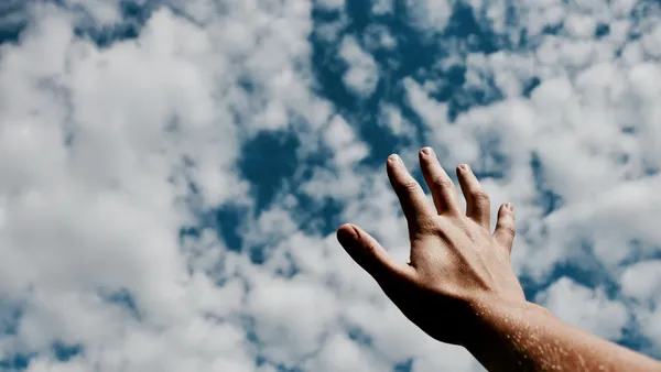Quelle: unsplash.com / Jeremy Perkins Hand, die nach den Wolken greift