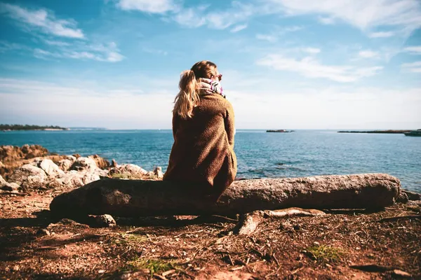 Quelle: Guillaume de Germain/Unsplash Frau in brauner Jacke blickt auf das Meer
