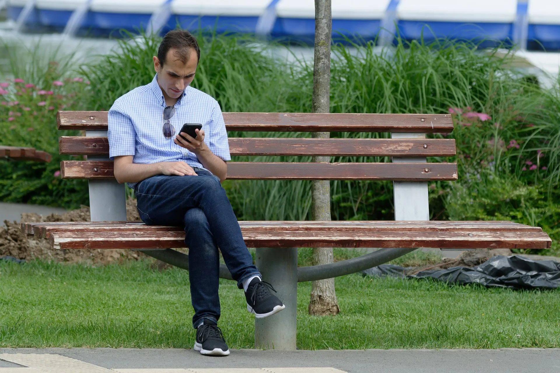 Quelle: Silviu/Pixabay Mann sitzt auf Parkbank mit Handy in der Hand
