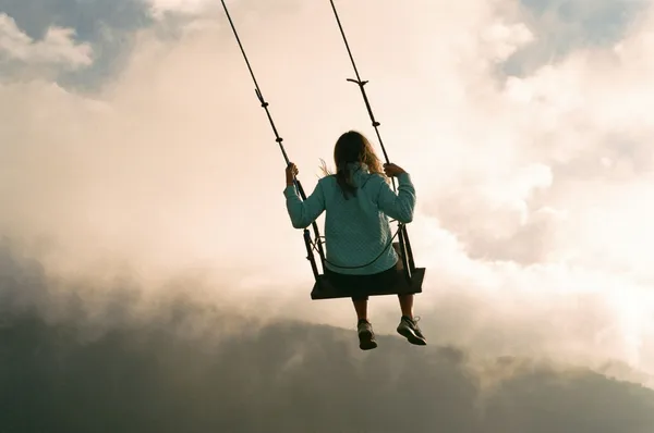 Quelle: Nick Monica/Unsplash Mädchen auf einer Schaukel mit Blick in den Himmel