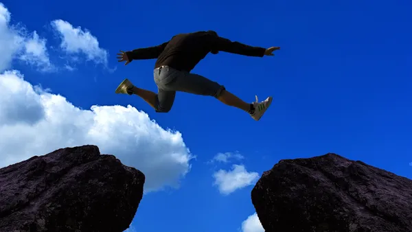 Mann springt von einem Stein zum anderen