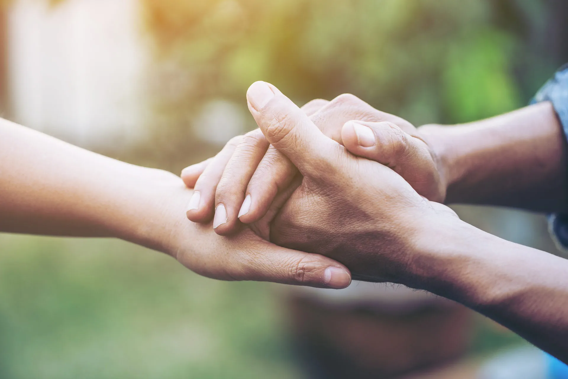 Eine Person hält mit ihren Hände die Hand einer einzelnen Person