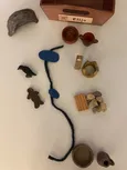 Godly Play Material zu Elija: In einer kleinen offenen Holzkiste befinden sich 1 blaue Wollschnur, 2 blaue Filzkreise, 2 Altäre (1 aus Holz, 1 aus 12 kleinen verleimten Steinen), 1 Teller & Krug mit einem Henkel (Ton, natur), 1 Schale & Krug mit zwei Henkeln (Ton, glasiert), 1 Holzfigur, 1 schwarzer Holzvogel, 1 goldfarbene Holzstele, 1 goldene Holzkrone und 1 Höhle (aus Ton)