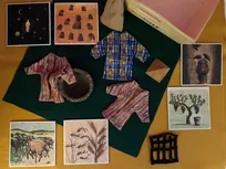 Godly Play Material zu Josef: In einer großen offenen Holzkiste befinden sich 6 Holztafeln mit Bildern, 1 hellbraunes Filztuch, 1 dunkelgrünes Filztuch, 1 dunkelbraunes Filzgitter (Gefängnis), 3 Gewänder, 1 Getreidesack, 1 kleine Holzpyramide und 1 Tonbrunnen