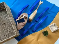 Godly Play Material zur Jona-Geschichte: Holzboot, blaue Filzunterlage, Walfisch aus Holz, Stadt Ninive aus Holz, Filzstreifen braun, Figur Jona, blaue Wellen aus Holz