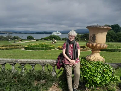 Dagmar Hasenkamp in einem kleinen Park. Im Hitergrund die Ms Deutschland